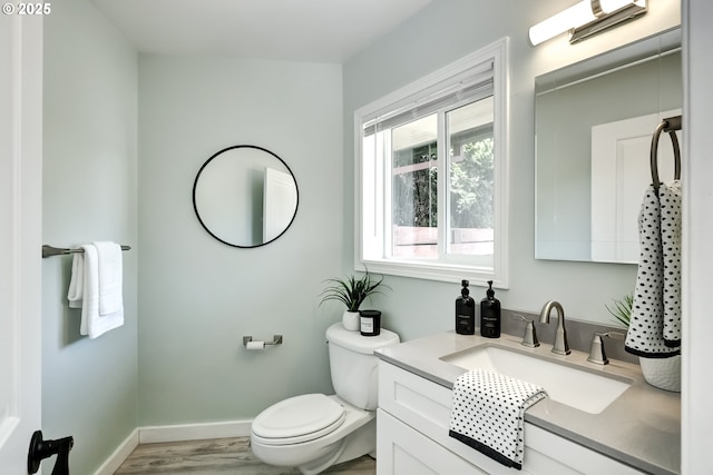 bathroom featuring toilet, wood finished floors, baseboards, and vanity