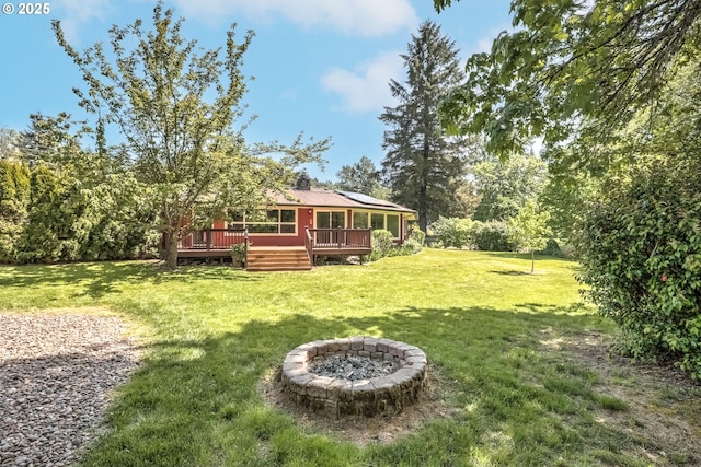 view of grassy yard with an outdoor fire pit and a wooden deck