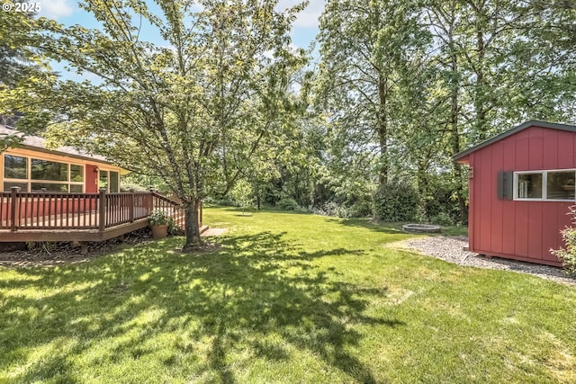 view of green lawn with a deck, an outdoor structure, and a storage unit