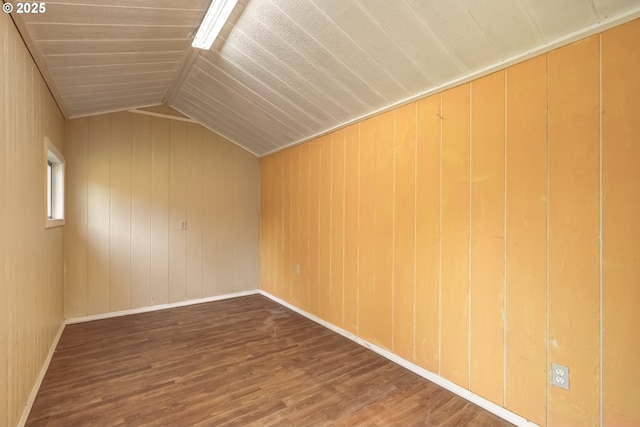 bonus room with wood finished floors, vaulted ceiling, baseboards, and wood walls
