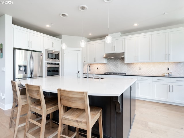 1856 NW Sierra Way, Camas, WA 98607 - kitchen with appliances with stainless steel finishes, under cabinet range hood, decorative backsplash, light wood-style flooring, and white cabinetry