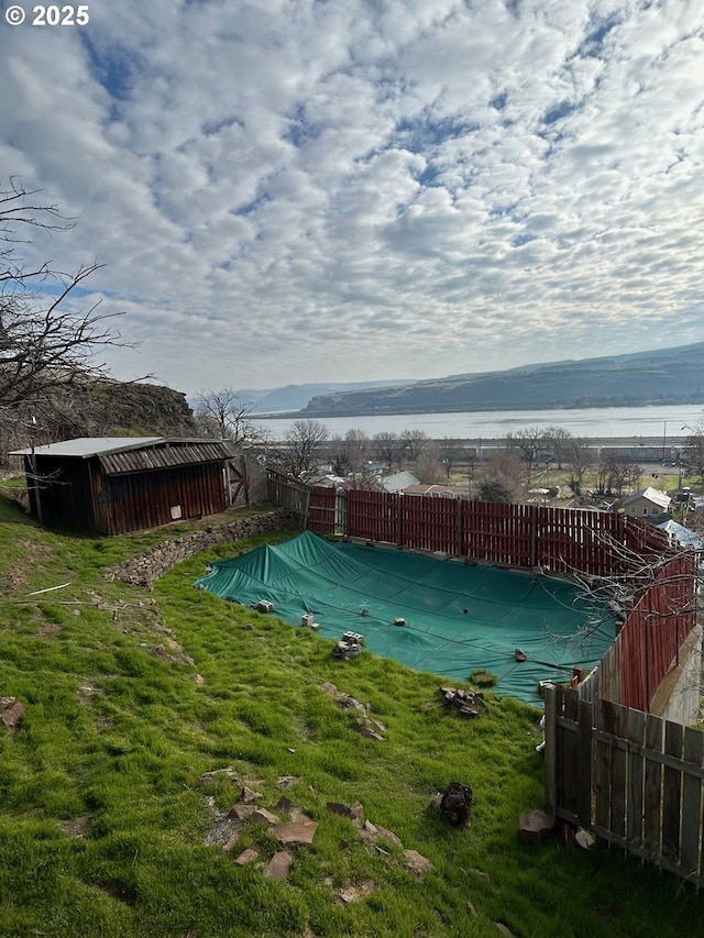 view of swimming pool featuring a yard, an outdoor structure, and a mountain view