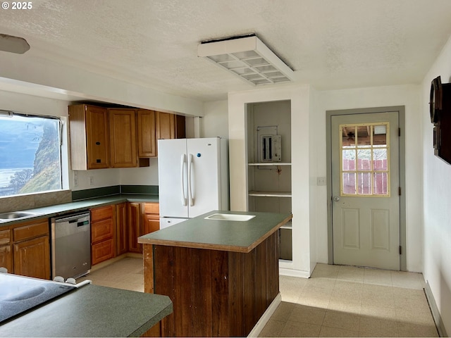 kitchen featuring sink, a textured ceiling, white refrigerator, dishwasher, and a kitchen island