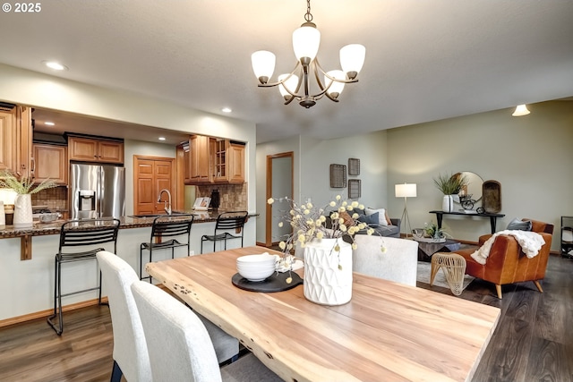 dining room featuring sink, dark wood-type flooring, and a chandelier