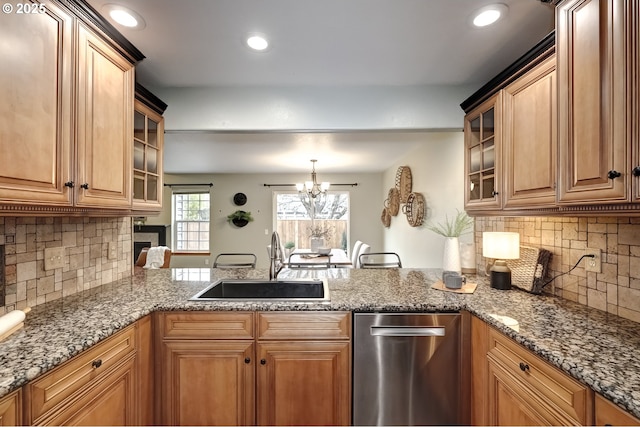 kitchen with dishwasher, sink, backsplash, dark stone counters, and kitchen peninsula