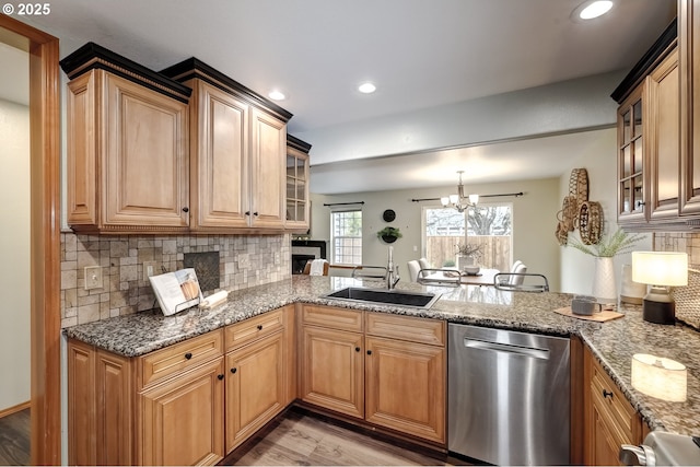 kitchen featuring sink, light hardwood / wood-style flooring, dishwasher, backsplash, and stone countertops