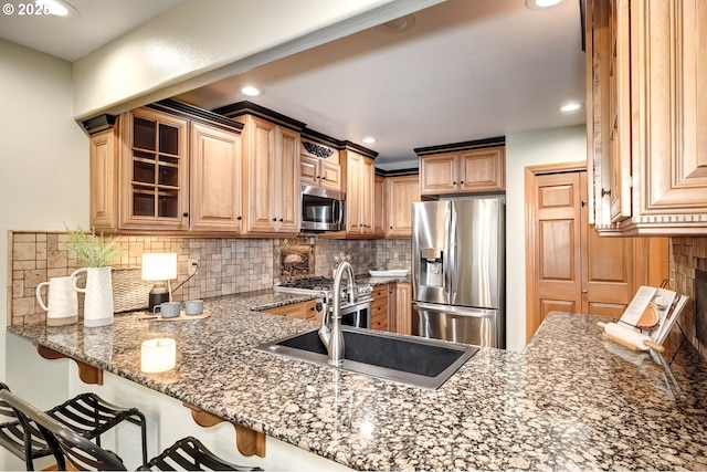 kitchen featuring a breakfast bar, tasteful backsplash, sink, dark stone countertops, and stainless steel appliances