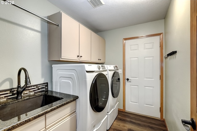 washroom featuring sink, cabinets, a textured ceiling, dark hardwood / wood-style flooring, and washing machine and dryer