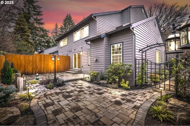 back house at dusk with a patio area