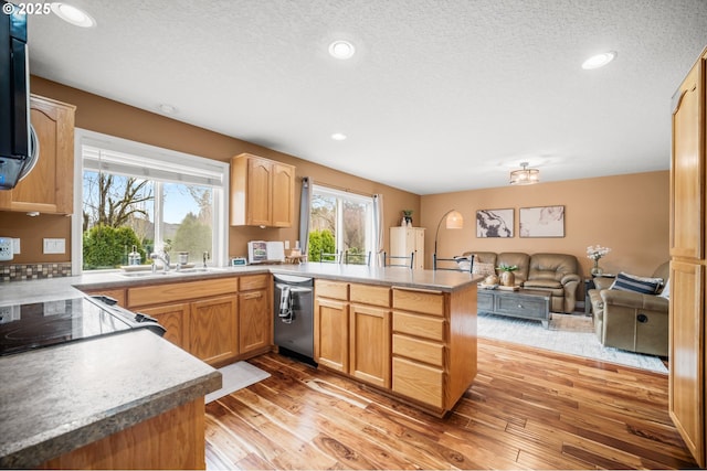 kitchen with a peninsula, light wood-style floors, a sink, and dishwasher