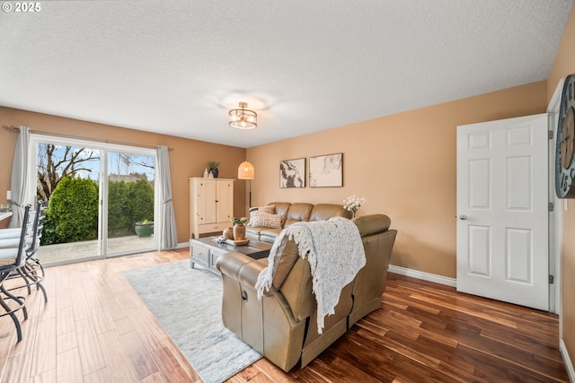 living room with a textured ceiling, wood finished floors, and baseboards