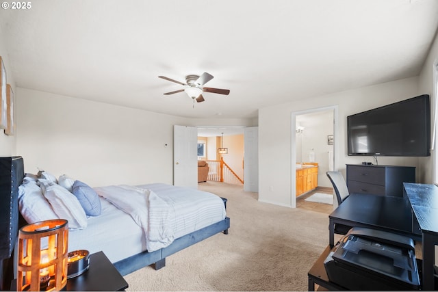 bedroom with baseboards, ensuite bath, a ceiling fan, and light colored carpet