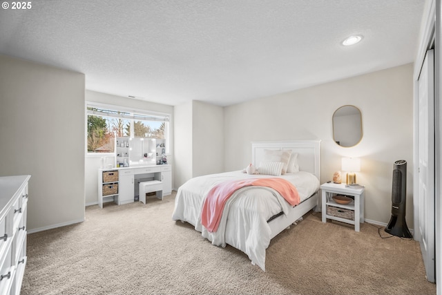 bedroom with light carpet, baseboards, and a textured ceiling