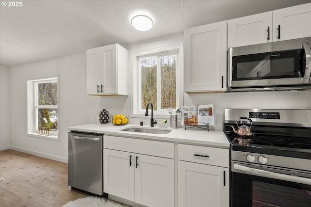 662 Cannavina Rd, Carson, WA 98610 - kitchen with stainless steel appliances, light wood finished floors, white cabinets, a textured ceiling, and light countertops