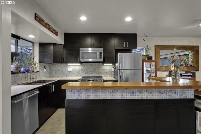 kitchen with a sink, dark cabinetry, stainless steel appliances, and tasteful backsplash