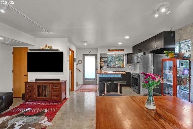 dining space featuring recessed lighting, rail lighting, concrete floors, and plenty of natural light