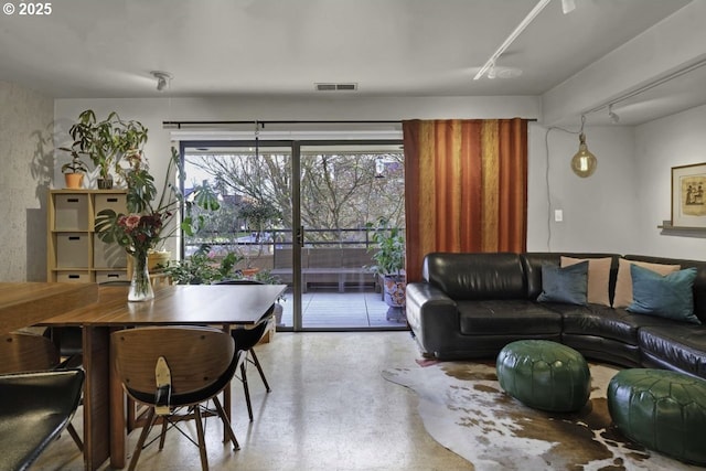 living area with visible vents, track lighting, and finished concrete flooring