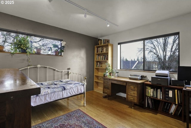 bedroom with rail lighting and wood finished floors