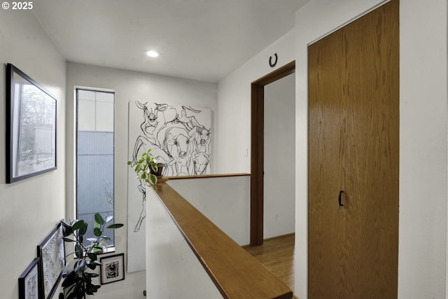 hall featuring recessed lighting, wood finished floors, and an upstairs landing