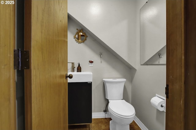 bathroom with baseboards, vanity, and toilet