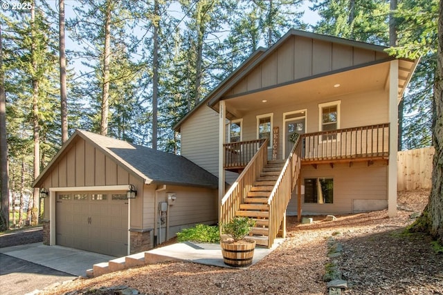 chalet / cabin with roof with shingles, covered porch, stairway, board and batten siding, and a garage