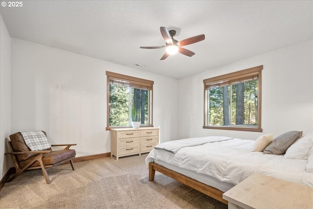 bedroom with light carpet, ceiling fan, visible vents, and baseboards