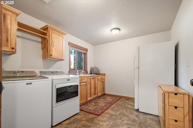 clothes washing area featuring cabinet space, baseboards, washer and clothes dryer, stone finish floor, and a sink