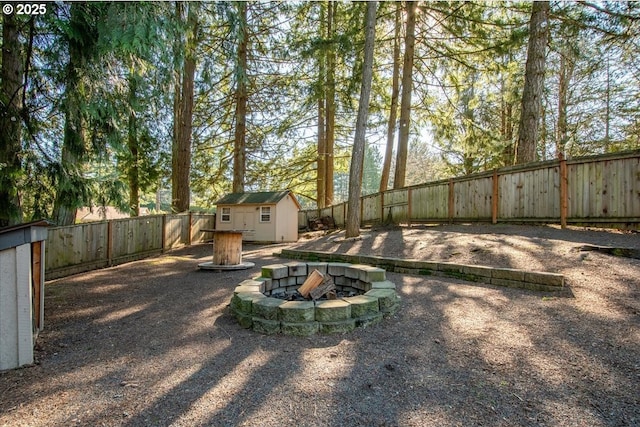 view of yard featuring a fenced backyard, an outdoor structure, a fire pit, and a storage shed