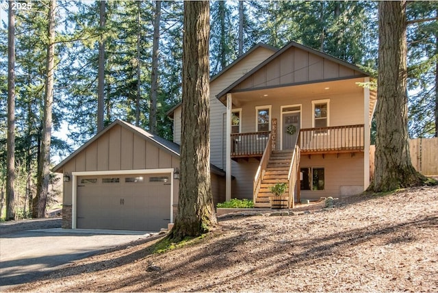 view of front of home with dirt driveway, stairway, an attached garage, covered porch, and board and batten siding