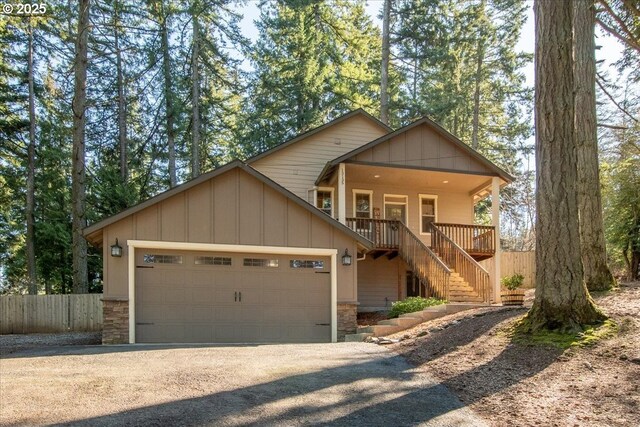 view of front of property featuring an attached garage, fence, stairs, driveway, and stone siding