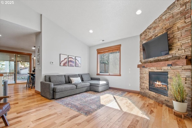 living room with high vaulted ceiling, a fireplace, wood finished floors, visible vents, and baseboards