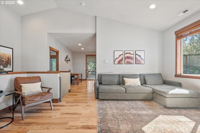 living area featuring high vaulted ceiling, recessed lighting, visible vents, and light wood-style floors