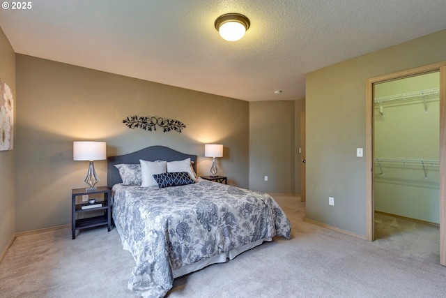 bedroom with a textured ceiling, light carpet, baseboards, a spacious closet, and a closet