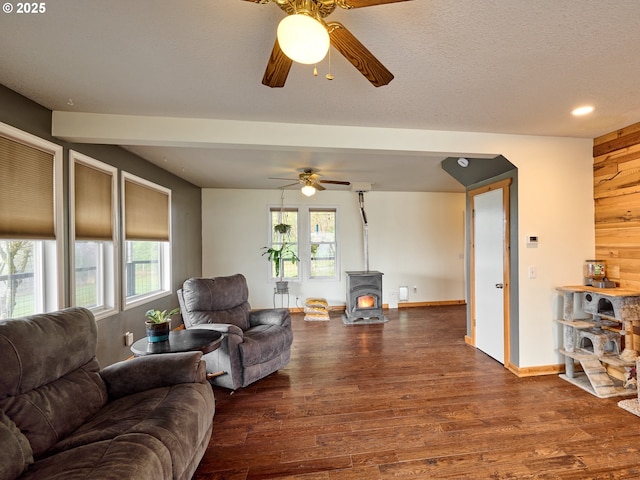 living room with baseboards, a ceiling fan, wood finished floors, a wood stove, and recessed lighting