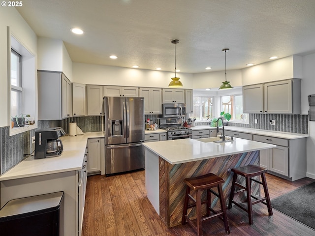 kitchen with a center island with sink, appliances with stainless steel finishes, light countertops, and gray cabinetry