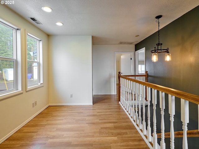 empty room with light wood-style flooring, visible vents, and baseboards