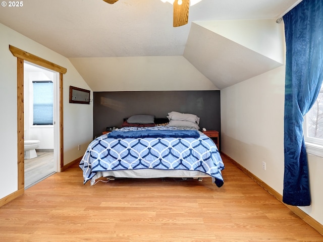 bedroom with light wood-type flooring, vaulted ceiling, and baseboards