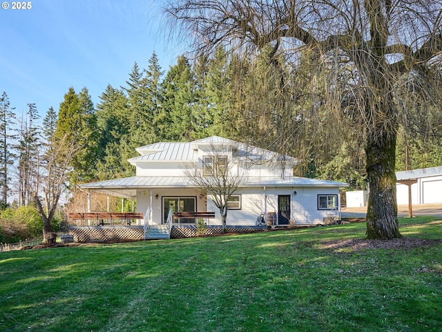 rear view of property with covered porch, a lawn, a standing seam roof, and metal roof