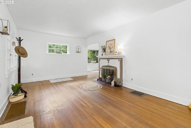1937 SE Knight St, Portland, OR 97202 - unfurnished living room with a fireplace with flush hearth, baseboards, wood finished floors, and arched walkways