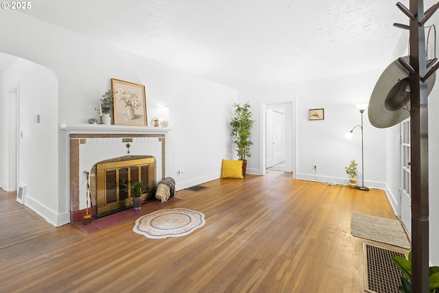 1937 SE Knight St, Portland, OR 97202 - unfurnished living room featuring wood finished floors, baseboards, arched walkways, and a fireplace