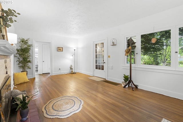 1937 SE Knight St, Portland, OR 97202 - foyer featuring wood finished floors, baseboards, a textured ceiling, and a fireplace