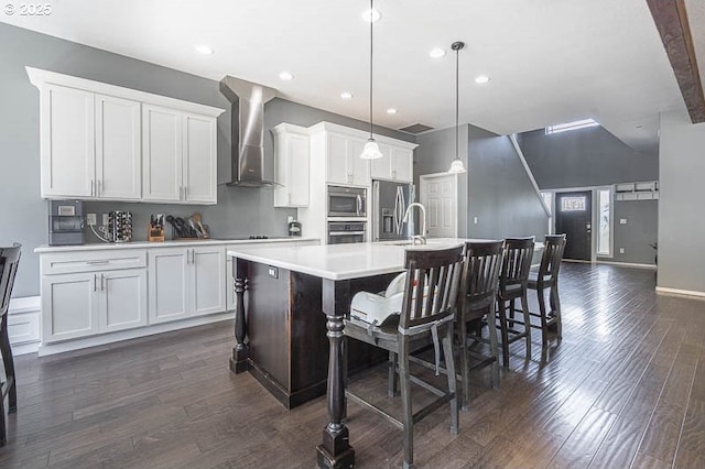 11364 James Way Dr SE, Aumsville, OR 97325 - kitchen with wall chimney range hood, appliances with stainless steel finishes, dark wood-style floors, light countertops, and an island with sink