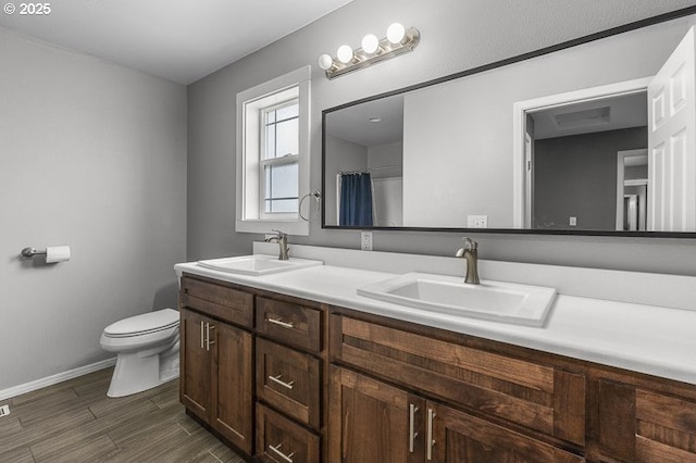 11364 James Way Dr SE, Aumsville, OR 97325 - bathroom featuring double vanity, toilet, baseboards, and wood finished floors