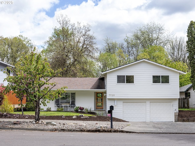tri-level home featuring a garage, a shingled roof, and concrete driveway