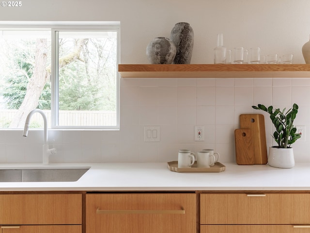 kitchen featuring a sink, light countertops, and backsplash