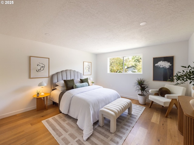 bedroom with light wood-type flooring, recessed lighting, a textured ceiling, and baseboards