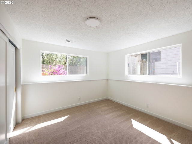 unfurnished bedroom with baseboards, light colored carpet, visible vents, and a closet