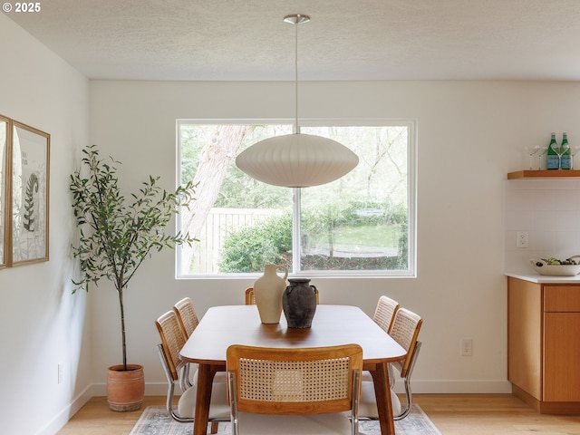 dining space featuring baseboards and light wood-type flooring
