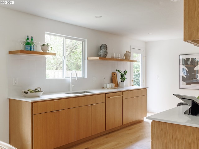 kitchen with open shelves, decorative backsplash, a sink, and light wood-style flooring