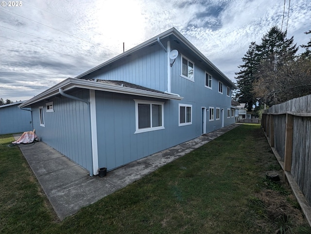 back of house featuring fence and a lawn